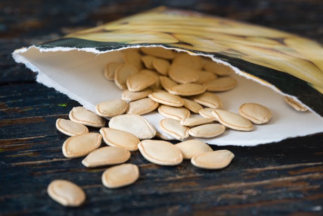 Close-Up Of Pumpkin Seeds Spilled From Paper Bag On Table