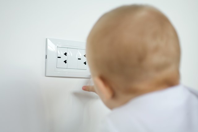 Baby touching electric outlet, rear view