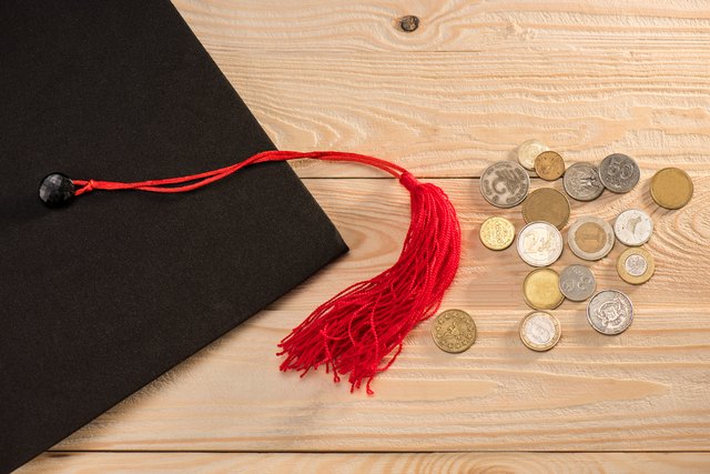 Close-up top view of graduation mortarboard and coins on wooden table, education concept