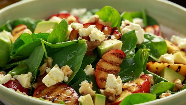 Summer Peach Salad with spinach, avocado, walnuts and feta cheese in rustic bowl. healthy food.