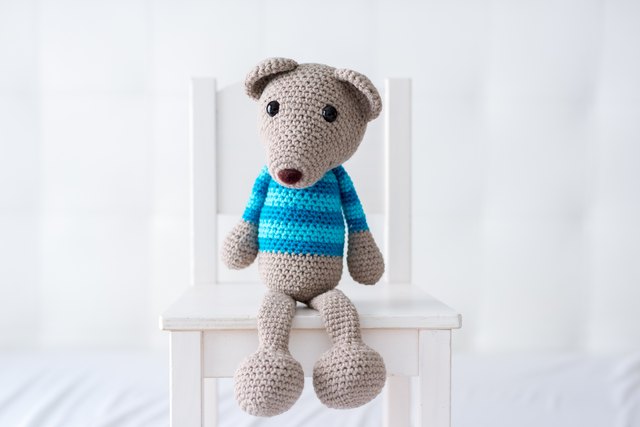 Handmade crocheted teddy bear with a striped shirt