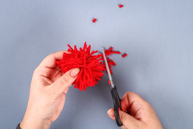 Red handmade diy monster pom pom from yarn, chenille stems in shape heart.