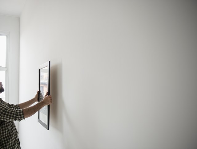 USA, New Jersey, Jersey City, Side view of man hanging picture on wall