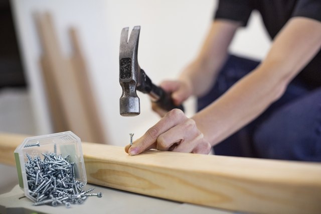 Midsection of female carpenter hammering nail into wooden plank