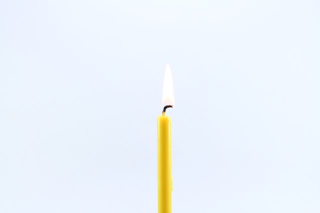 Close-Up Of Burning Candle Against White Background