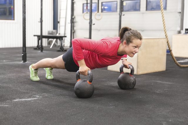Young woman trains pushups with kettlebells