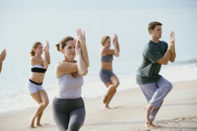Group of people performing yoga on the beach