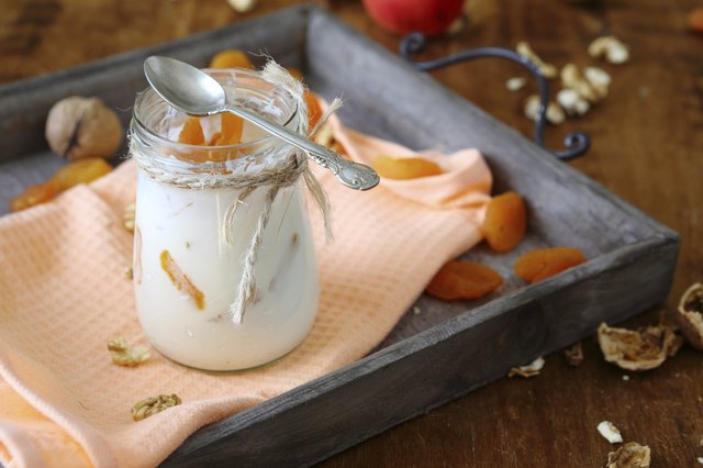 jar fresh yogurt with nuts and apricots on old tray