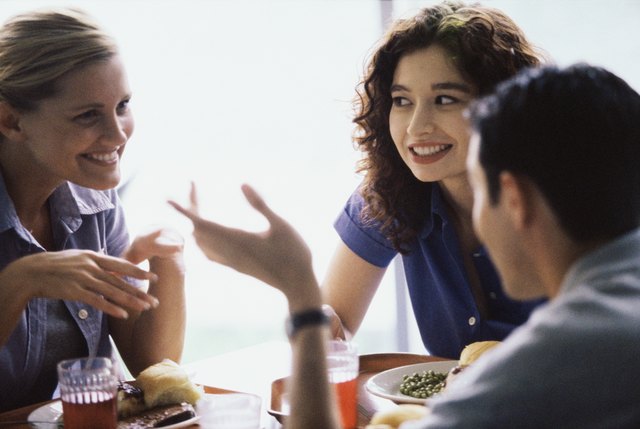 Two young women and a young man sitting in a restaurant