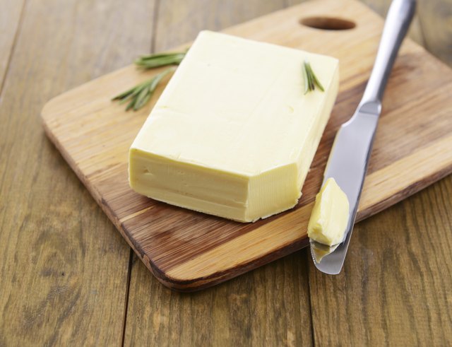 Tasty butter on wooden cutting board