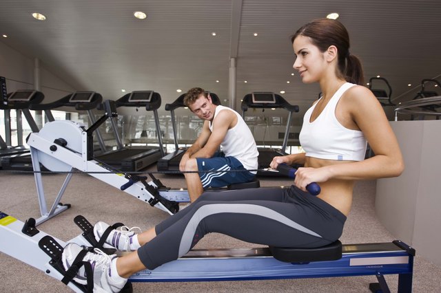 Man watching woman on rowing machine at gym