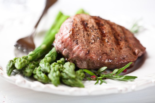 Juicy grilled steak on green asparagus