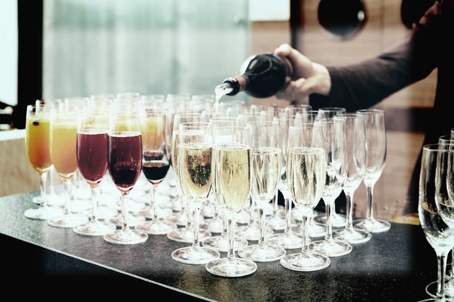 Bartender is pouring sparkling wine in glasses, toned