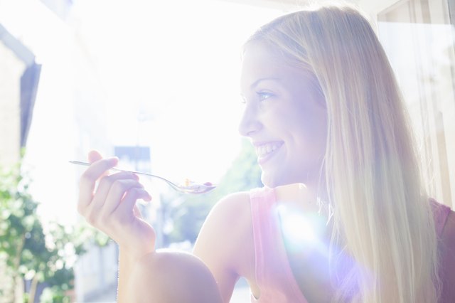 Smiling woman eating bowl of cereal