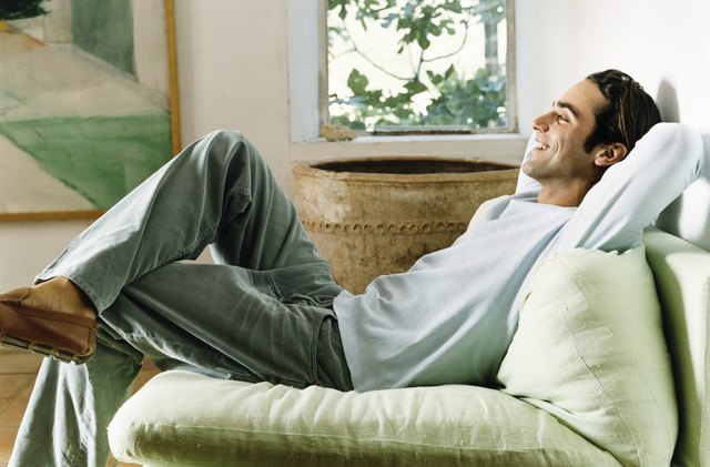 Man Relaxing in an Armchair in a Living Room with His Hands Behind His Head