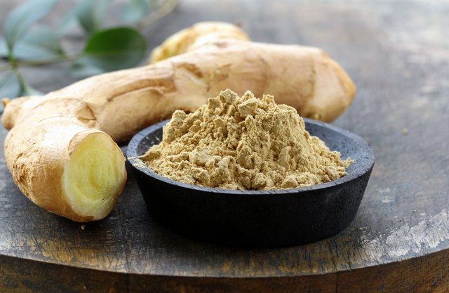 ground ginger (spice) and fresh on a wooden board