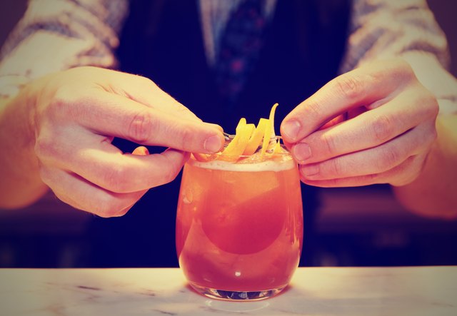 Barman is decorating a cocktail, toned