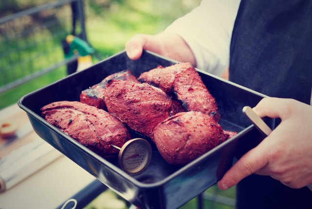 Chef holding a tray with cooked meat, toned