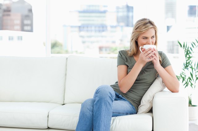 Woman holding a mug up to her nose as she looks to the side while sitting