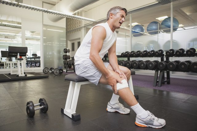 Injured man gripping his knee in the weights room