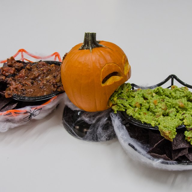 Small pumpkin with guacamole on one side and salsa on the other