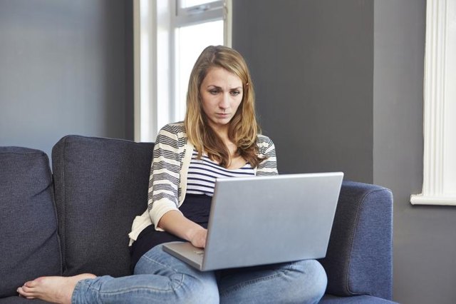 A young woman is browsing on her laptop.