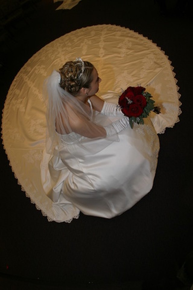 A bride walking down the aisle with a veil train attached to her dress.