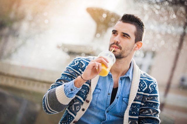 Young man drinking a yellow smoothie