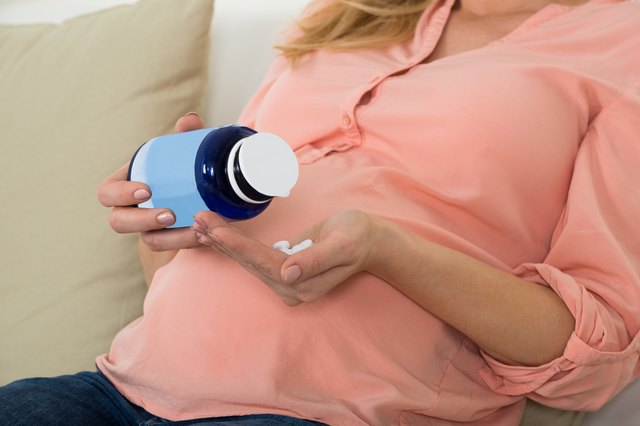 Pregnant Woman Pouring Pills In Hand From Bottle
