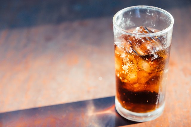 Glass of cola with ice on wooden table