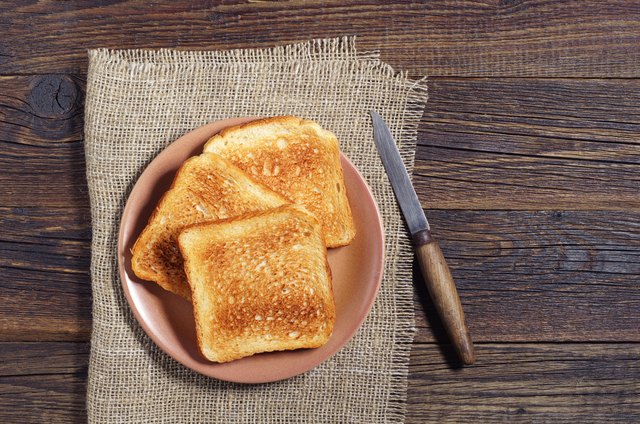 Slices of toasted bread and knife on dark wooden table, top view