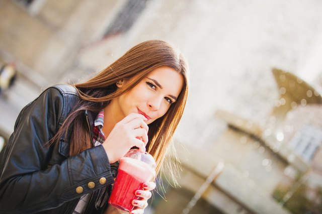 Happy woman outside drinking a smoothie
