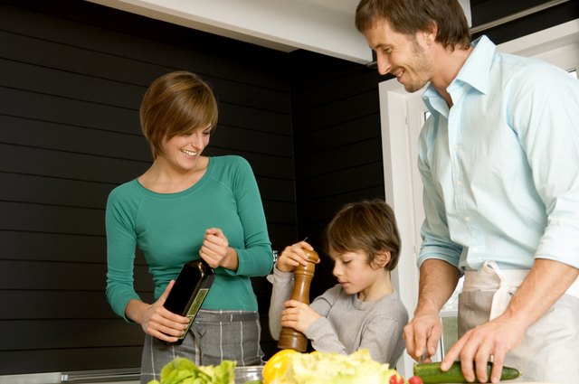 Mid adult man and a young woman preparing food with their son in a kitchen