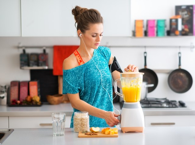 Fit woman in kitchen making a smoothie