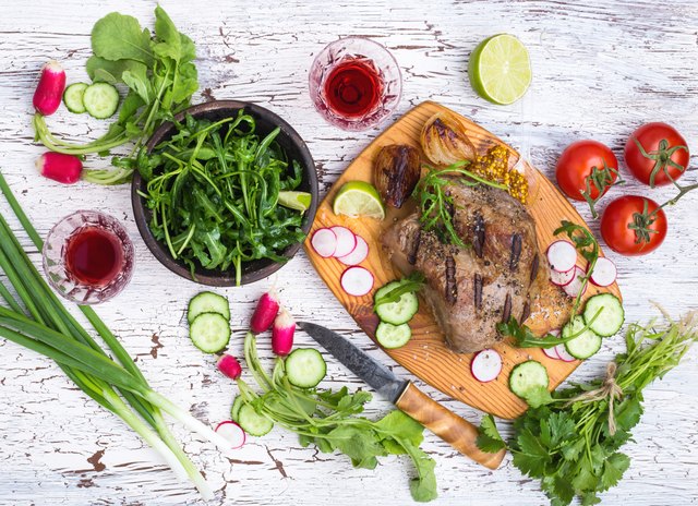 Grilled juicy meat with vegetables on a white rustic wooden background viewed from above, picnic table