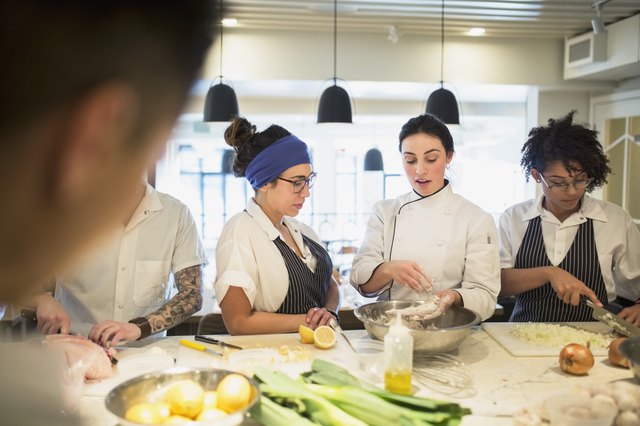 Chef mentoring students in restaurant kitchen