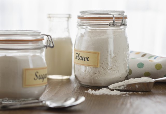 Glass jars of sugar, cream, and flour on counter