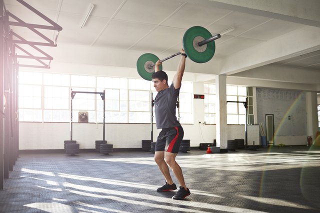 Crossfit instructor lifting barbell at urban gym