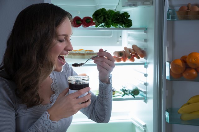Woman Eating In Front Of Fridge