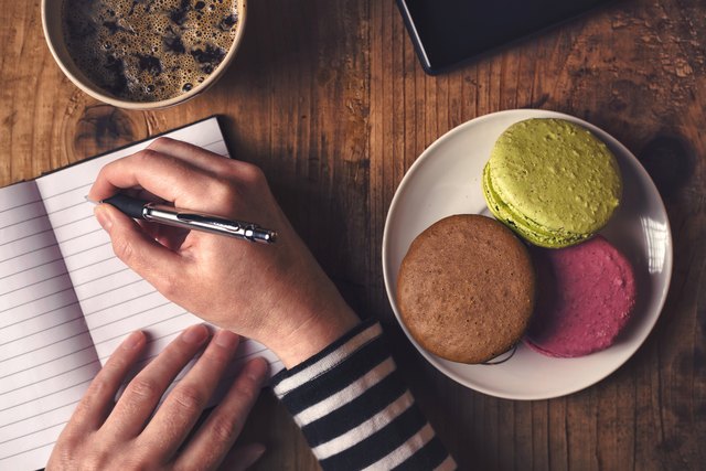 Woman writing in notebook during breakfast, top view