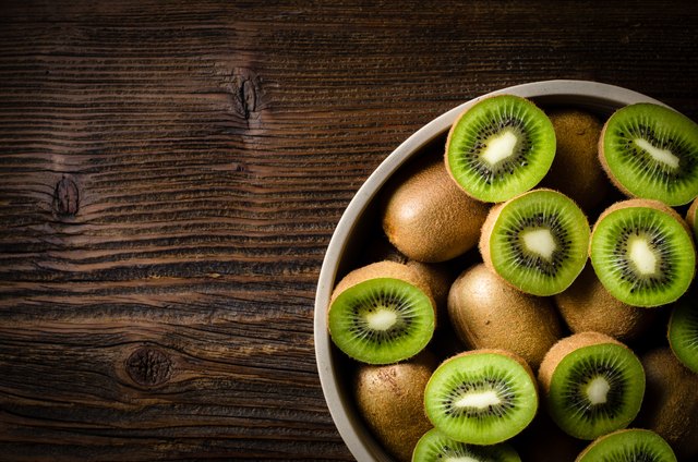 Kiwi fruits in bowl over wooden background