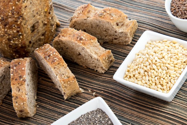 Freshly baked bread chopped up next to some grains