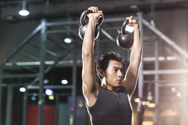 Young man training with kettlebells in crossfit gym