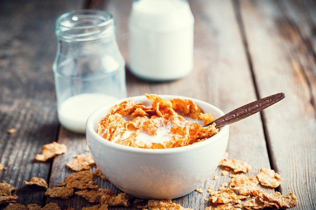 Breakfast cereal wheat flakes in bowl and milk bottles