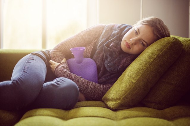 Teenage girl with hot water bottle on sofa
