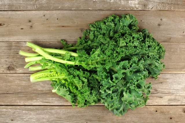 Bunch of fresh green kale over an aged wooden background. Overhead view.