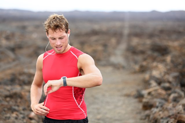 Running athlete man looking at smartwatch heart rate monitor GPS