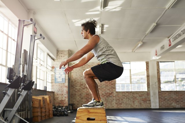 Man doing box jump in crossfit gym