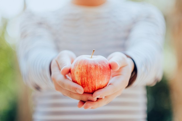 Man holding a fresh red apple in hand in nature
