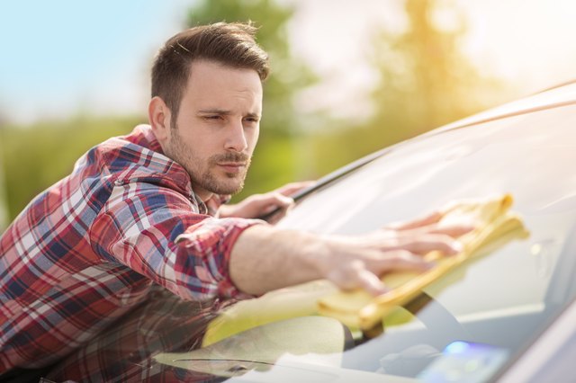 Young man cleaning his car outdoors